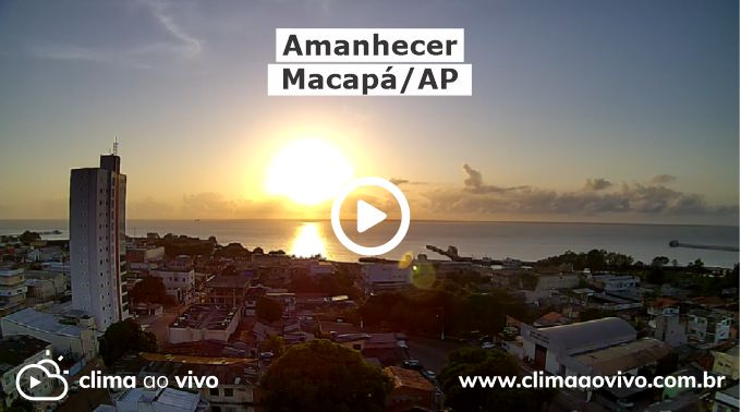 Amanhecer em Macapá/AP com a cidade a frente e o sol nascendo em cima do mar ao fundo. Textos na imagem "Amanhecer em Macapá/AP", "www.climaaovivo.com.br" e logo do Clima ao Vivo